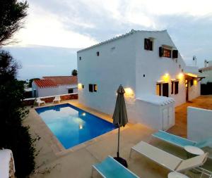 a villa with a swimming pool in front of a house at San Colomban in Sant Lluis