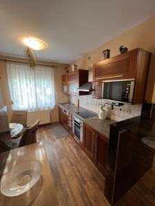 a large kitchen with wooden cabinets and a table at Bedi Apartmanház in Nagykanizsa