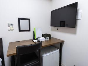 a desk with a television on a wall with a chair at Tabist Ishinomaki in Ishinomaki