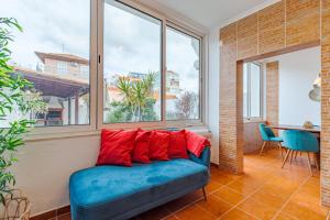 a blue couch with red pillows in a room with windows at Setúbal Oasis House, By Home Match in Setúbal