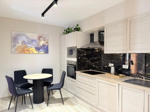 a kitchen with white cabinets and a table and chairs at Elko Apartments & Rooms in Golem