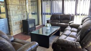 a living room with leather couches and a stove at 128 Clarens Golf Villa in Clarens