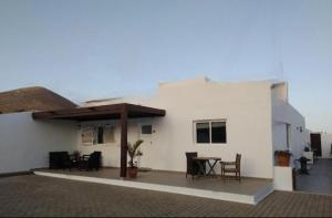 a white house with a table and chairs on a patio at Casita Blum in La Asomada