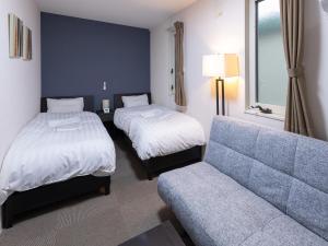 a hotel room with two beds and a couch at Tabist Ishinomaki in Ishinomaki