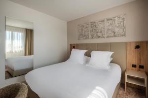a bedroom with a large white bed and a chair at The Originals city, Hôtel Harys in Vichy +38 photos