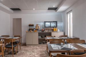 a dining room with tables and chairs and a counter at The Originals city, Hôtel Harys in Vichy