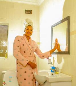 a woman standing in a bathroom in front of a mirror at Lion Haven Guest House in Harare