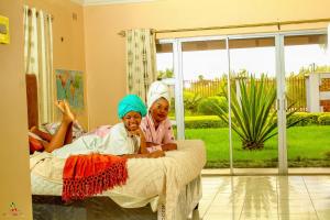 two girls sitting on a bed in a room at Lion Haven Guest House in Harare