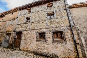 an old stone building with windows on a street at Casona del Tambor in Calatañazor