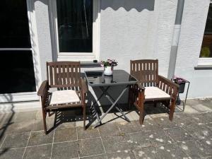 a patio table with two chairs and a table with flowers at Ferienwohnung Haus Mäsch in Wellen +8 photos