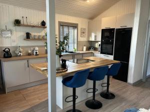 a kitchen with a wooden counter and blue bar stools at Fig Tree Lodge in Ellonby