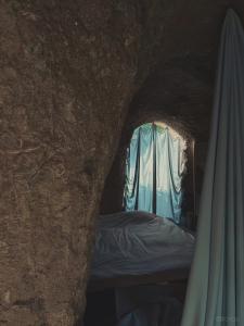 eine Höhle mit einem Bett und einem Fenster mit einem Vorhang in der Unterkunft maison owl in Ube