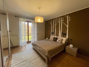 a bedroom with a bed with a tree mural on the wall at Villa Glory Mountain Lake Iseo Hospitality in Bossico