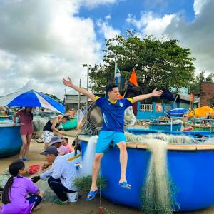 a man is jumping off of a blue boat at Bason Hotel Long Hải in Long Hai