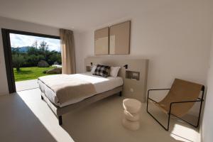 a bedroom with a bed and a chair and a window at Villa Adeona in Zonza +34 photos