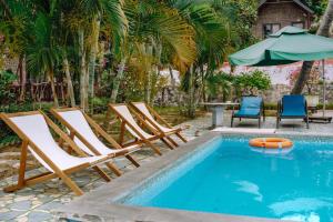 a group of chairs and an umbrella next to a swimming pool at Cat Ba Spring Homestay in Cat Ba
