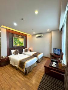 a hotel room with two beds and a television at Gllant Villa Hà Nội in Hanoi