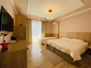 a hotel room with two beds and a television at Elko Apartments & Rooms in Golem