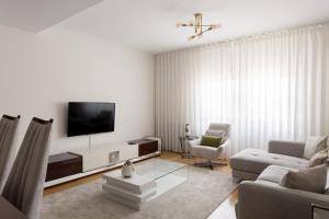 a white living room with a tv and a couch at Colinas Premium 3BR in Odivelas