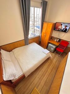 a bedroom with a bed and a desk and a window at Hoa Cattleya Hotel in Da Lat +8 photos