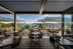 a restaurant with tables and chairs and mountains in the background at Hilton Lake Como in Como