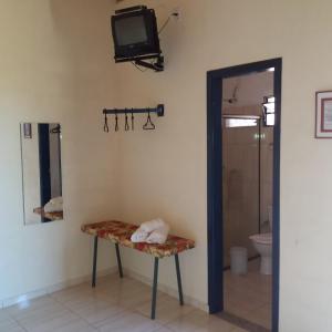 a bathroom with a toilet and a tv on the wall at Pousada Desfiladeiro da Serra in Serra Negra