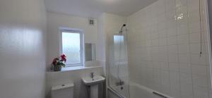 a white bathroom with a sink and a toilet at Cozy Flat with Parking in Goodmayes