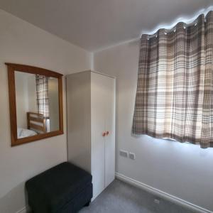 a room with a mirror and a chair in it at Cozy Flat with Parking in Goodmayes