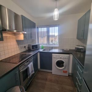 a kitchen with a washing machine and a sink at Cozy Flat with Parking in Goodmayes