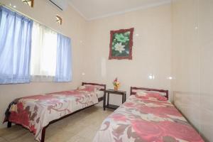 a bedroom with two beds and a window and a table at Villa Riens Dream in Karangasem