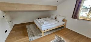 a small bed in a room with a window at Ferienwohnung "Krainsbergkogel" - Edles Dachgeschossapartment mit Bergblick in Schliersee +18 photos