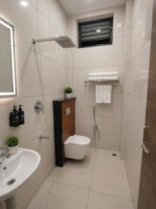 a white bathroom with a toilet and a sink at Shri Valli Residency in Palni