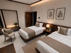 a hotel room with two beds and a chair at Shri Valli Residency in Palni