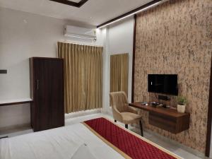 a bedroom with a bed and a desk and a television at Shri Valli Residency in Palni