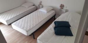 two white beds in a room with a blue pillow at Maison à proximité des plages in Bénodet