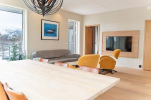 a living room with a table and chairs and a tv at Exclusive apartment in Lofoten in Svolvær