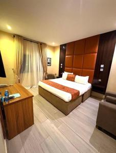 a hotel room with a large bed and a desk at de brit hotel in Benin City +13 photos
