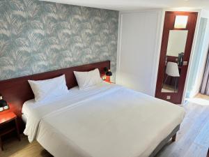a bedroom with a large white bed and a wall at Kyriad Bordeaux Lormont in Lormont