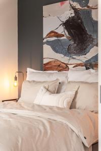 a bed with white sheets and a painting on the wall at Exclusive apartment in Lofoten in Svolvær