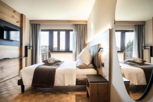 a hotel room with two beds and a balcony at Hotel Arcobaleno in Fai della Paganella