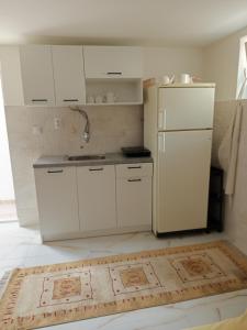 a kitchen with white cabinets and a refrigerator at Fantazija Tešnjar Apartment in Valjevo