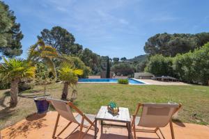 a patio with two chairs and a table and a pool at Bosc in Pals