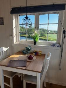a dining room table with chairs and a window at Möllergårdens Stugor in Ängelholm