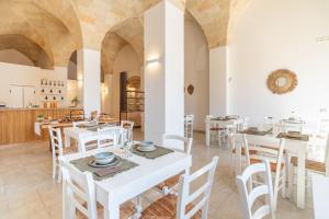 a dining room with white tables and chairs at Mediterranea Residence in Nardò