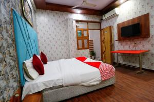a bedroom with a bed with red pillows and a desk at Hotel Hindon Residency "Couple Friendly" in Ghaziabad
