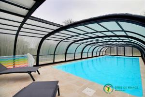 a swimming pool with a retractable roof at Ty brestivan in Theix