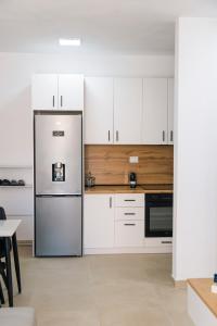 a kitchen with white cabinets and a stainless steel refrigerator at Salt & Serenity Apartment in Orikum +11 photos