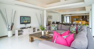 a living room with a couch and pink pillows at Dhevatara Residence Beachfront Villas in Mae Nam