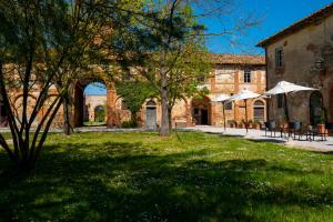 a building with tables and umbrellas in a yard at Tenuta La Fratta in Sinalunga