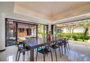 a dining room with a large black table and chairs at Dhevatara Residence Beachfront Villas in Mae Nam